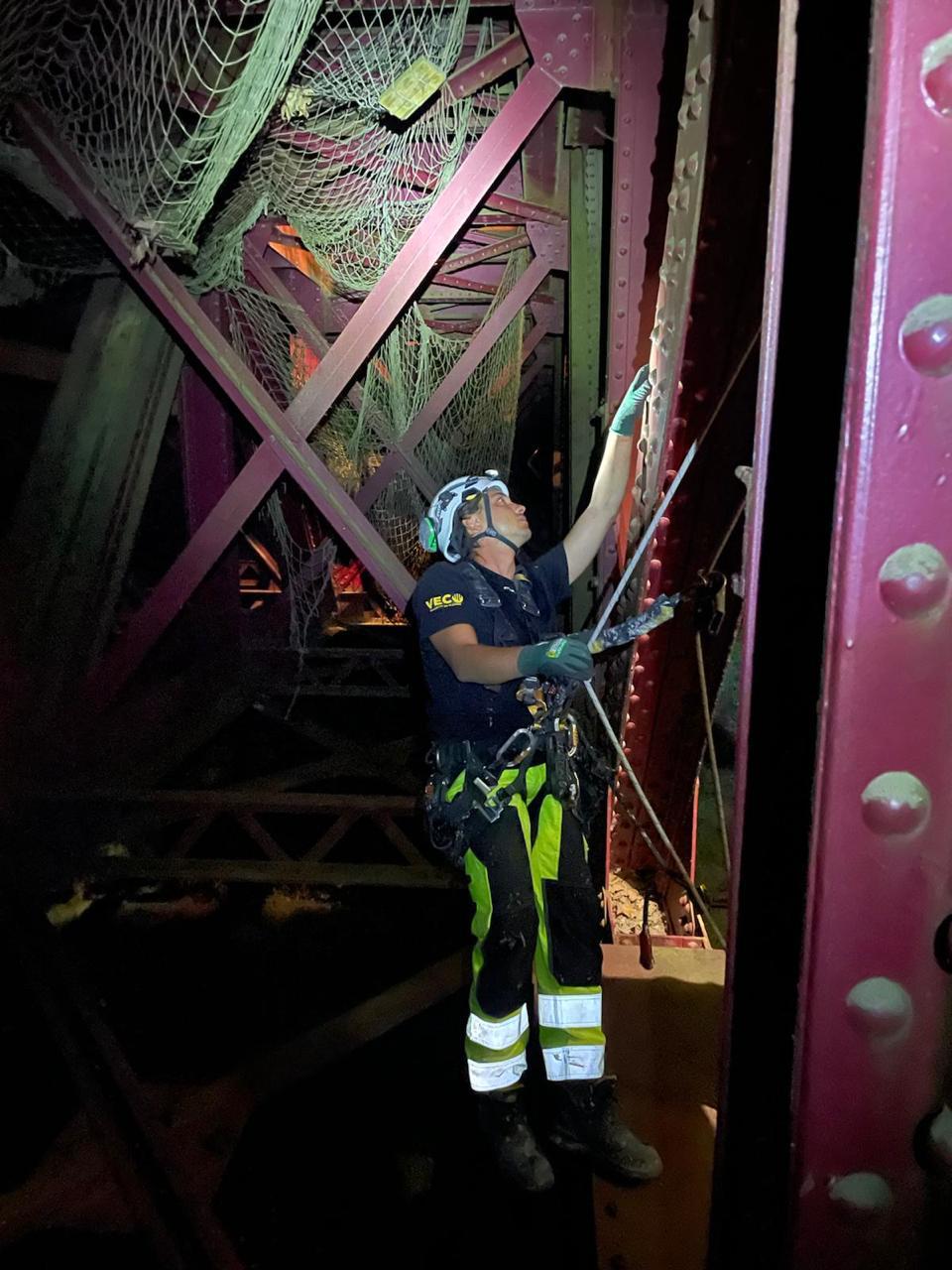 Técnico VECO inspeccionando estructura metálica de puente en trabajos nocturnos