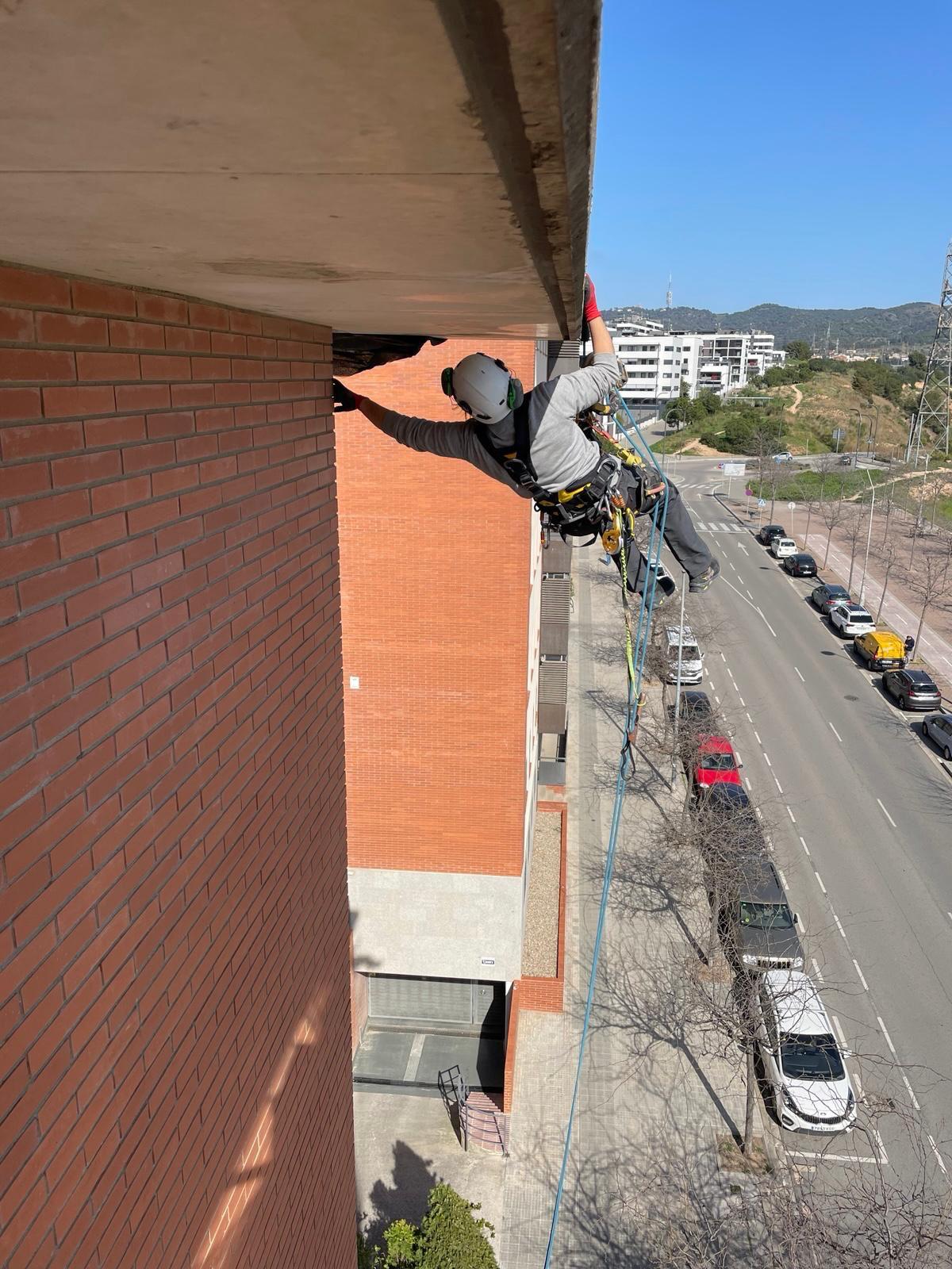 Técnico VECO inspeccionando y reparando cornisa de edificio con acceso por cuerdas